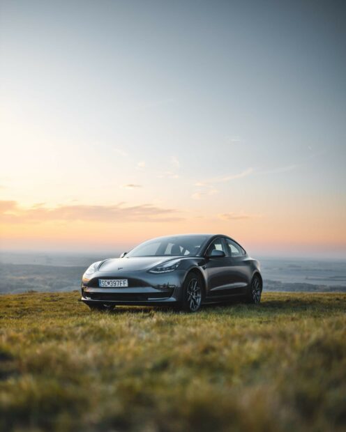 A Tesla Model Y parked on a grassy hill during sunset showcasing the Tesla Model Y design
