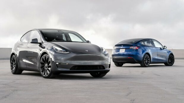 Two Tesla Model Y cars parked on empty concrete under cloudy sky