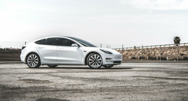 White Tesla Model Y parked on an empty lot under a clear sky