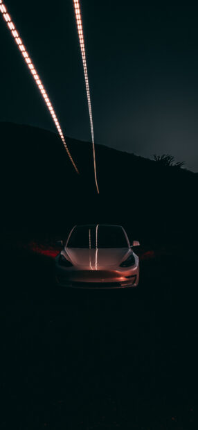 Tesla Model Y driving at night with light trails above the vehicle