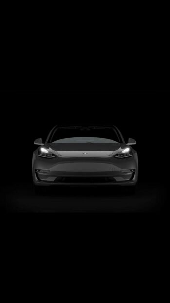 Black Tesla Model Y front view with headlights on in a dark setting