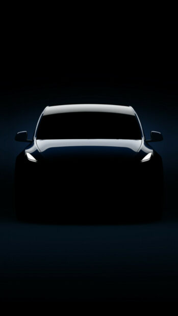 Dark silhouette of Tesla Model Y with headlights on in a front view