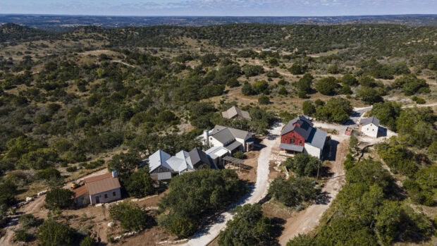 A scenic view of Texas Hill Country with rustic houses and dense greenery surrounding the area
