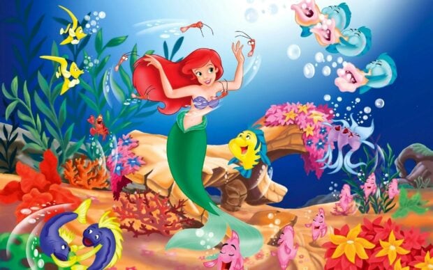 Ariel the little mermaid swimming underwater surrounded by colorful sea creatures and coral reefs