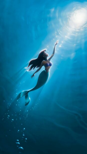 The little mermaid swimming towards the surface reaching for light underwater