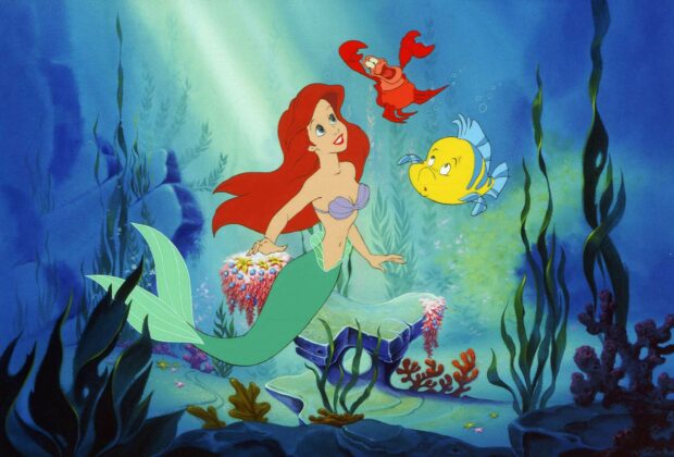 Ariel as the little mermaid swimming underwater with her friends Sebastian and Flounder