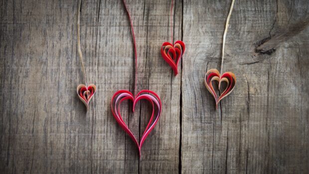 Red paper hearts hanging on wooden surface with Valentine decorations