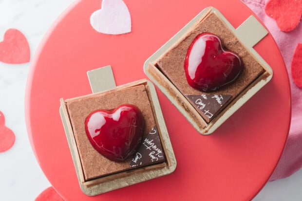 Two chocolate desserts with red heart decoration on a red plate for Valentine celebration