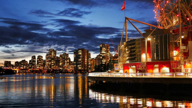 Night view of Vancouver Canada city skyline with illuminated buildings and waterfront reflections