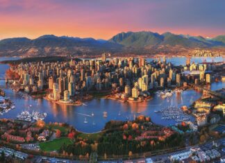 A panoramic view of Vancouver cityscape with mountains and water surrounding the urban area at sunset