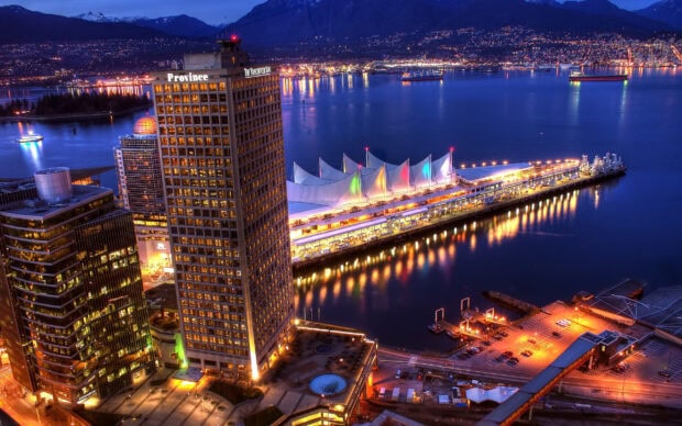 Night view of Vancouver Canada city skyline with waterfront and mountains in the background