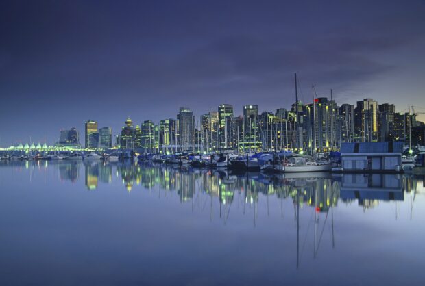 Vancouver Canada city skyline with marina and boats reflecting on calm water at dusk