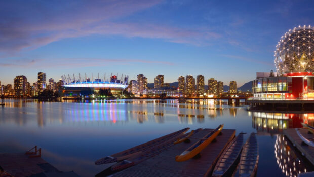 Vancouver city skyline with illuminated buildings and calm water reflections at dusk in Canada