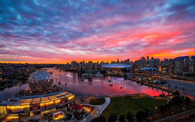 The Vancouver Canada cityscape with a vibrant sunset sky reflecting over the water and illuminated buildings