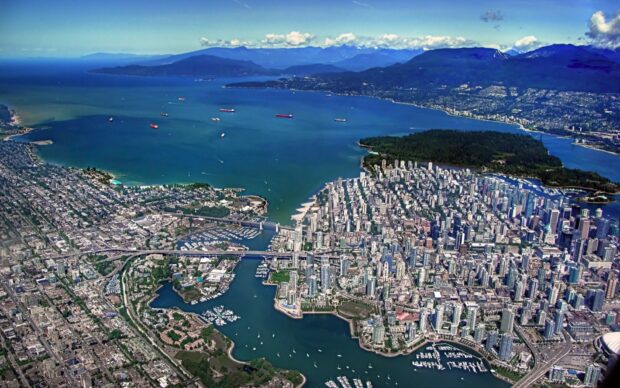 Aerial view of Vancouver Canada cityscape with mountains and water surrounding the urban area