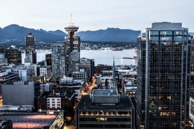 Downtown Vancouver Canada cityscape with mountains in the background at dusk