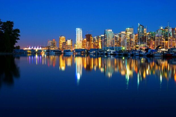 Downtown Vancouver Canada skyline reflecting over calm water at night