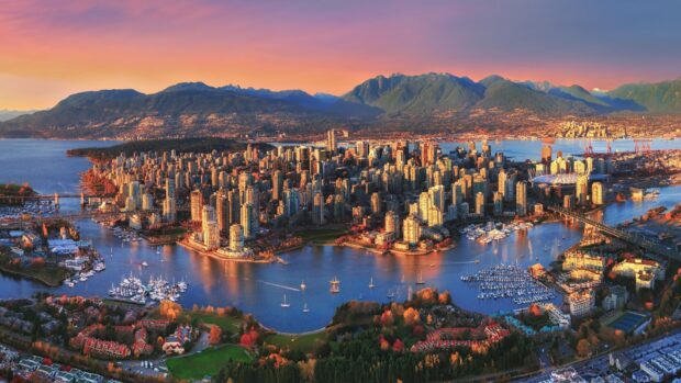 A panoramic view of Vancouver cityscape with mountains and water bodies at sunset in Canada