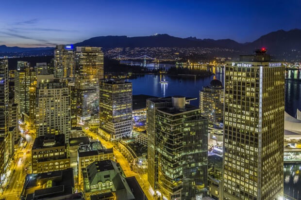 Night view of Vancouver Canada skyline with city lights and mountains in the background