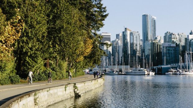 People biking and walking along a waterfront path with trees in Vancouver Canada