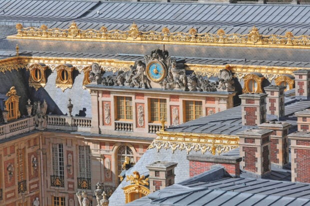 Detailed Versailles architecture with ornate clock and golden decorations on rooftops