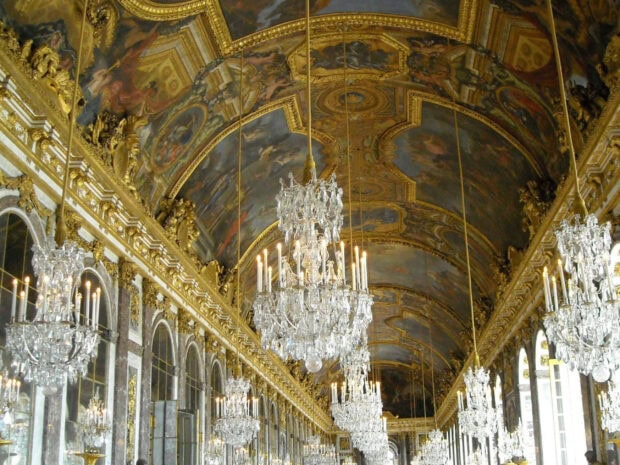 The interior of Versailles with crystal chandeliers and ornate ceiling paintings