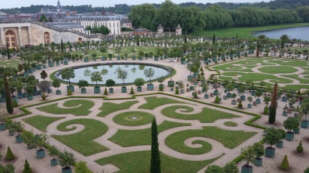 Ornate garden of Versailles with symmetrical hedges and circular pond in the landscape