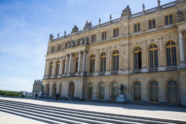 The Versailles building with detailed architecture and statues under a clear blue sky