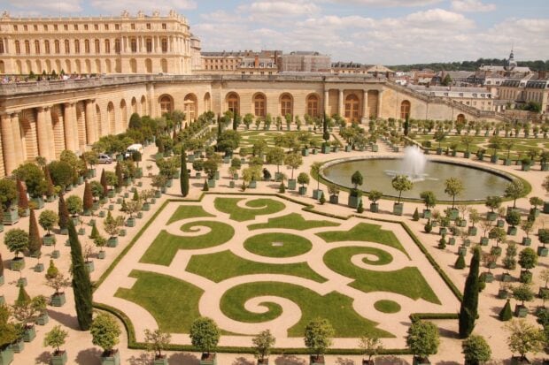 Beautiful Versailles garden with symmetrical greenery and fountain under a clear sky