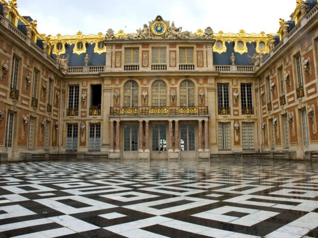 The Versailles palace courtyard featuring intricate marble flooring and ornate golden facade elements