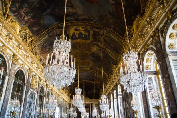 The ornate Versailles ceiling with crystal chandeliers and detailed gold decorations