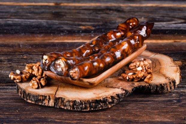 A close up view of walnuts in a wooden tray placed on a rustic wooden surface