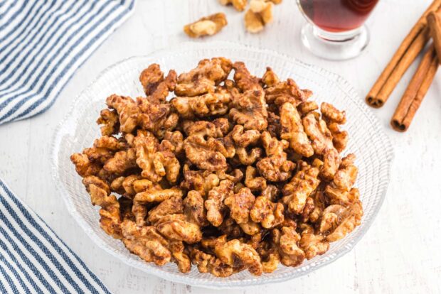 A bowl of roasted walnuts seasoned with spices on a white tablecloth background
