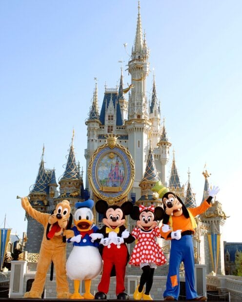 Walt Disney characters standing in front of Cinderella castle at Walt Disney World Resort