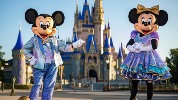 Mickey and Minnie posing in front of the Walt Disney World Resort castle dressed in colorful outfits