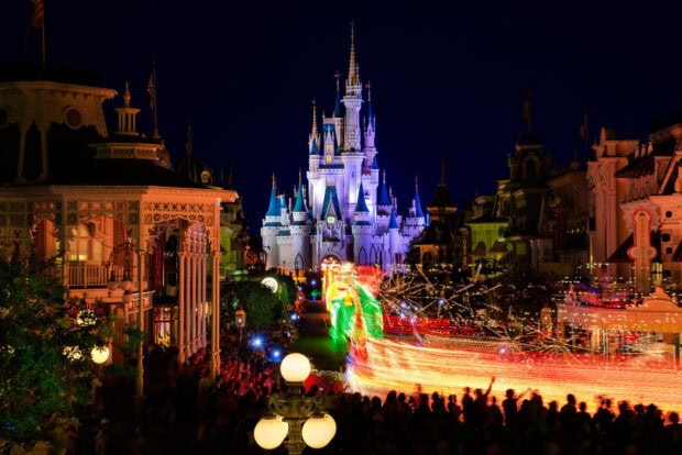 Night view of Walt Disney World Resort with illuminated castle and parade lights