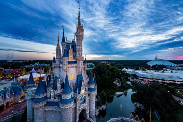 The Walt Disney World Resort castle stands tall at dusk under a vibrant sky in Walt Disney World Resort
