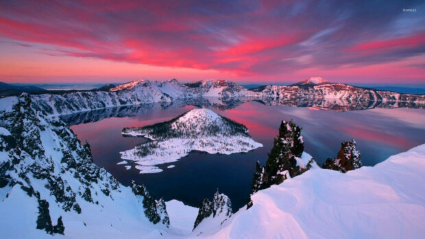 Snowy mountain landscape with a winter lake under a colorful sunset sky