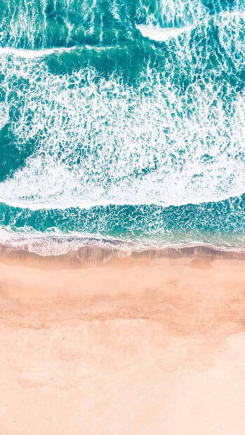 Aerial view of turquoise ocean waves crashing on sandy beach with summer vibes