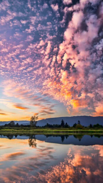 Colorful summer sky reflecting over calm lake during sunset