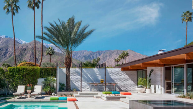 A modern Palm Springs patio featuring lush palm trees and stunning mountain views under a clear blue sky