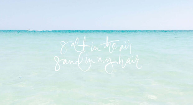 Calm pastel summer ocean scene with salt in the air and sand in my hair text