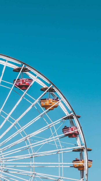 Colorful ferris wheel cabins under clear blue sky in a preppy summer setting