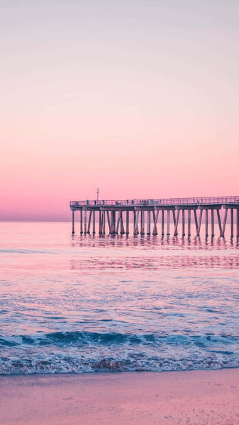 Pink sky and peaceful ocean scenery with pier at sunset summer scene