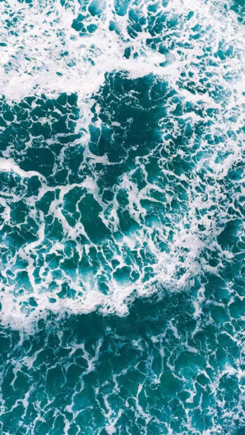 Turquoise ocean waves create a vibrant summer scene with frothy white foam and deep blue water
