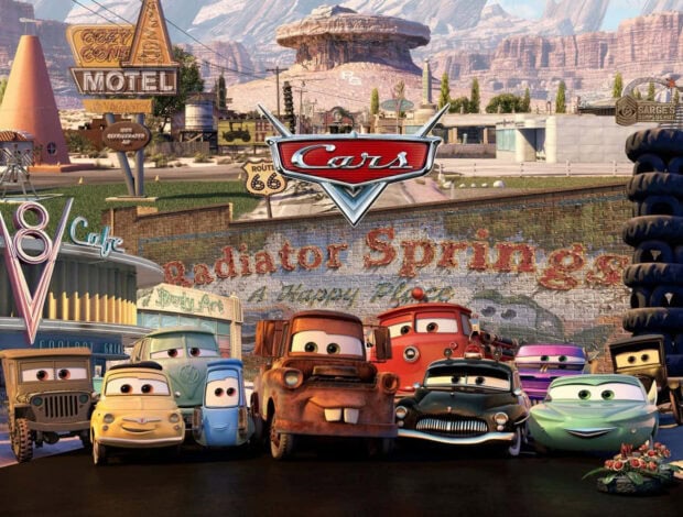 Animated characters from Radiator Springs gathered in front of a scenic desert townscape