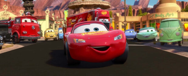 Lightning McQueen and friends racing through Radiator Springs town in a vibrant scene