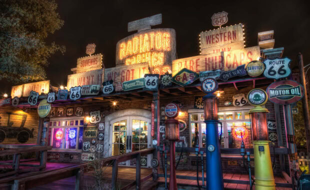 Radiator Springs gas station with vintage Route 66 signs illuminated at night