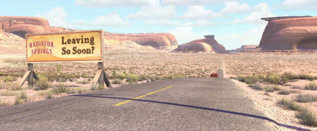 The Radiator Springs road with a sign saying Leaving So Soon and desert landscape in the background