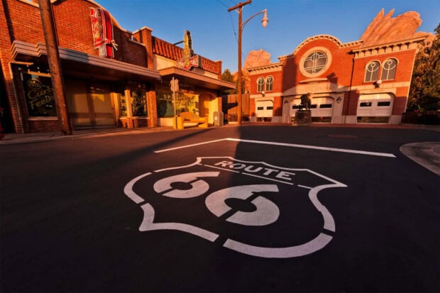 The Route 66 sign on the road in Radiator Springs town with classic brick buildings